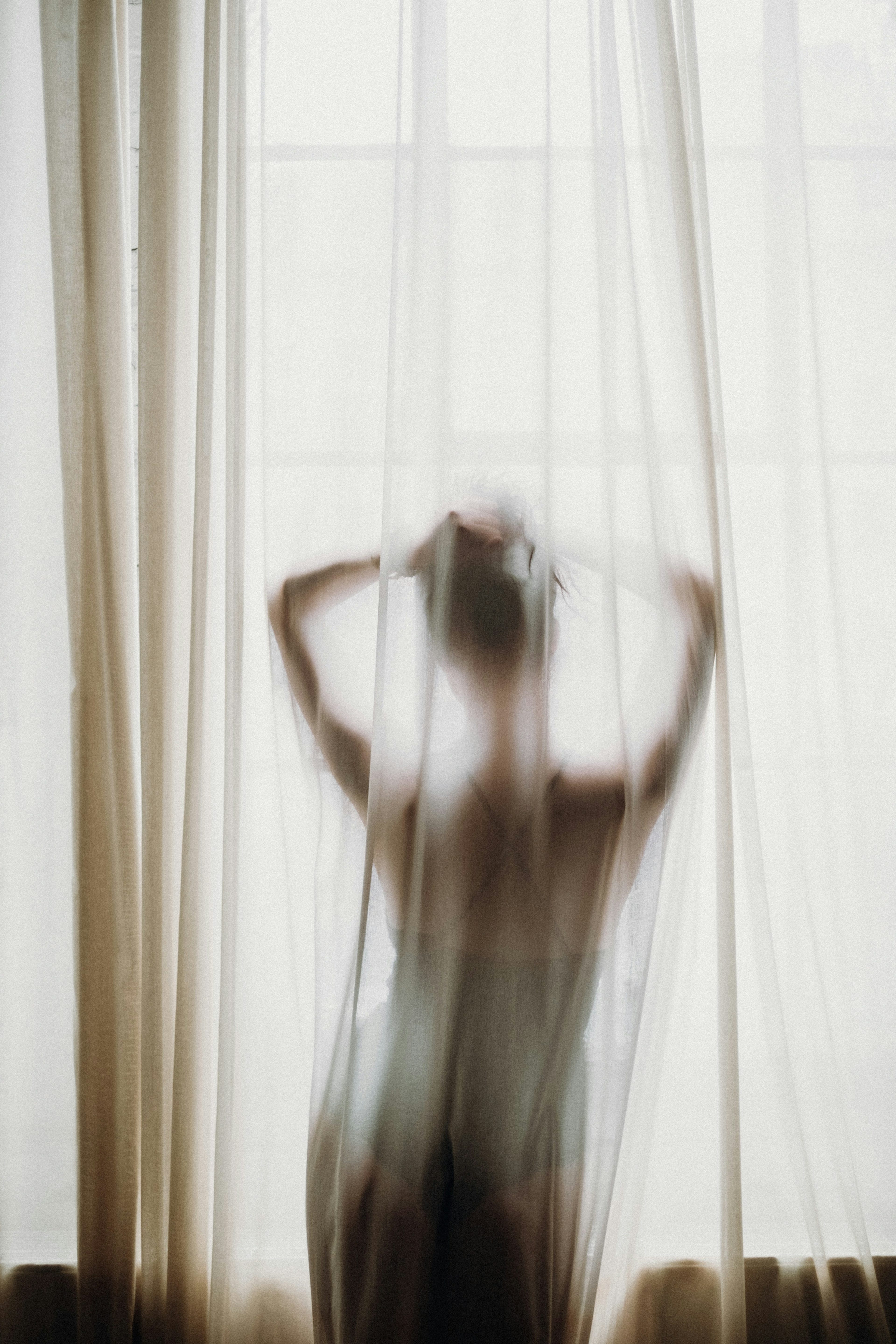 Silhouette of a woman behind a sheer white sheet